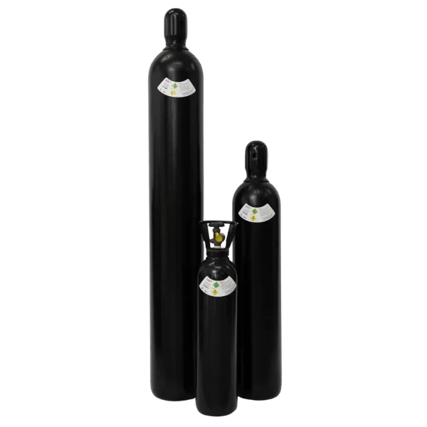 Three black gas cylinders of varying sizes stand against a dark background; all bear yellow and green hazard labels.